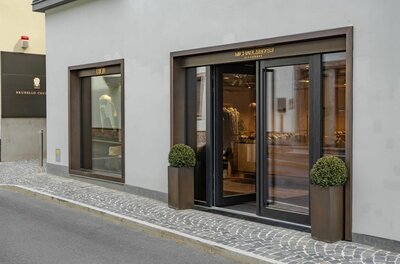 Modegeschäft Michael Meyer Eingangsbereich eines Modegeschäfts mit Glasfront und dunklen Metallrahmen an einer gepflasterten Straße.