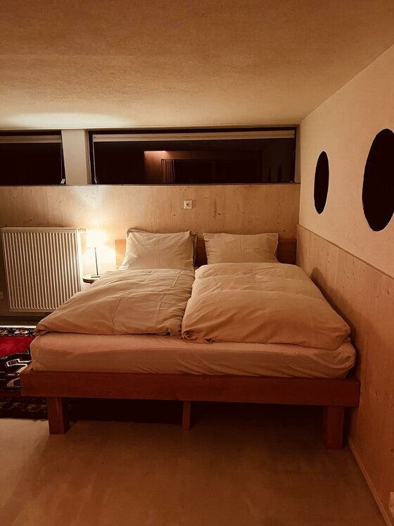 Schlafbereich im Pool House Doppelbett aus Holz in einem modern gestalteten Zimmer mit Holzverkleidung und indirekter Beleuchtung.