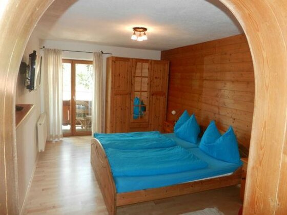 Schlafzimmer Ferienwohnung Henntalhof Schlafzimmer mit Doppelbett, blauer Bettwäsche, Holzschrank und holzgetäfelter Wand.