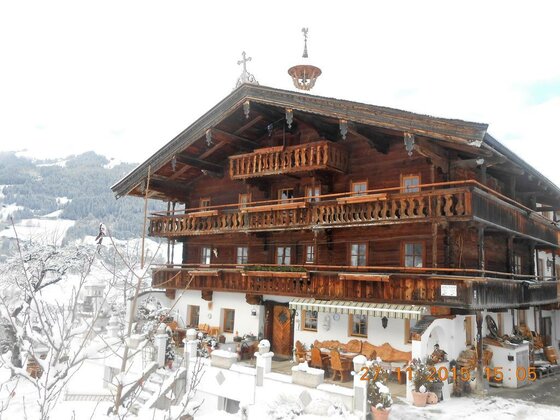 Talhof im Winter Mehrstöckiges Holzhaus mit Balkonen in verschneiter Berglandschaft.