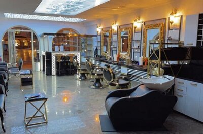 Golden Style Herren Friseur Innenansicht eines modern eingerichteten Barbershops mit goldenen Spiegeln und schwarzen Friseurstühlen.