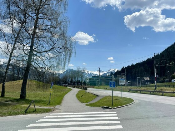 Zebrastreifen und asphaltierter Radweg neben einer Straße mit Blick auf schneebedeckte Berge.