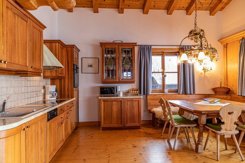 Rustikale Holzküche mit angrenzender Essecke und Holzbalkendecke.