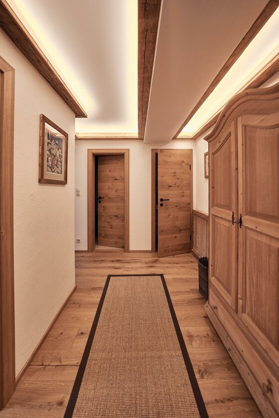 Flur der Ferienwohnung Flur mit Holzboden, zwei Holztüren, einem großen Schrank und indirekter Deckenbeleuchtung.