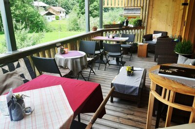 KunstTraum Cafe - Terrasse Eine gemütliche Terrasse mit Tischen und Stühlen. Im Hintergrund sieht man eine grüne Landschaft und einige Gebäude.