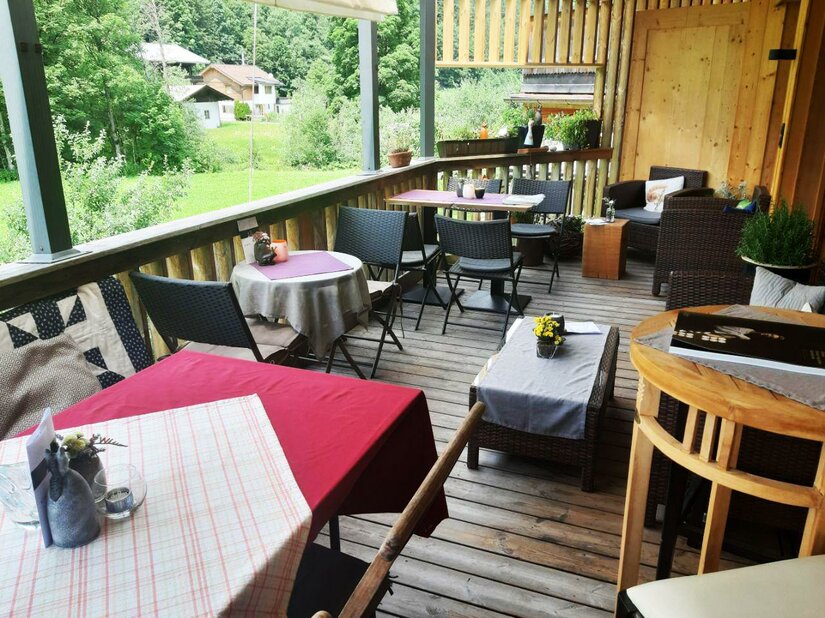 KunstTraum Cafe - Terrasse Eine gemütliche Terrasse mit Tischen und Stühlen. Im Hintergrund sieht man eine grüne Landschaft und einige Gebäude.