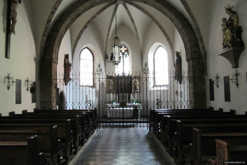 Katharinenkirche Eine ruhige Kirche mit hohen Gewölben und Holzbank. Der Altarbereich ist von einem Gitter umgeben, und das Licht fällt durch die Fenster hinein.