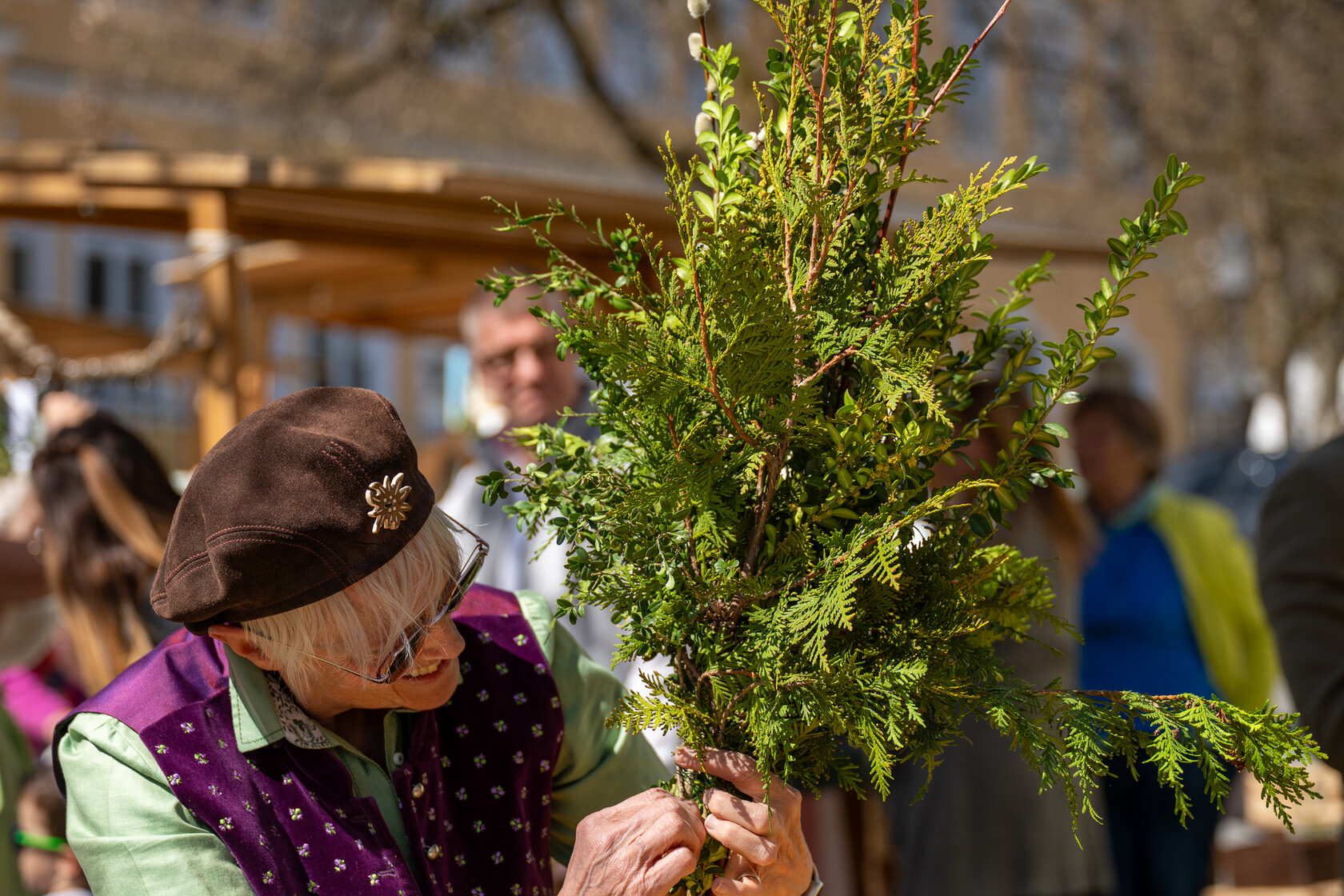 A woman is making a palm frond bouquet from green twigs