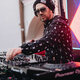 Der DJ trägt stylische Sonnenbrillen und einen Hut, während er die Beats für die tanzende Menge anpasst.