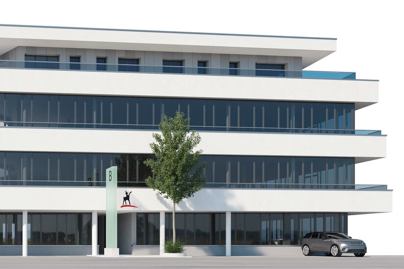 Kitzbüheler Anzeiger Ein modernes Bürogebäude mit großen Fensterfronten und einem klaren Design. Vor dem Gebäude steht ein Baum und ein Auto parkt auf der Straße.