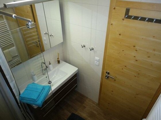 Modernes Badezimmer mit weißem Waschbecken, Spiegelschrank und Holztür.