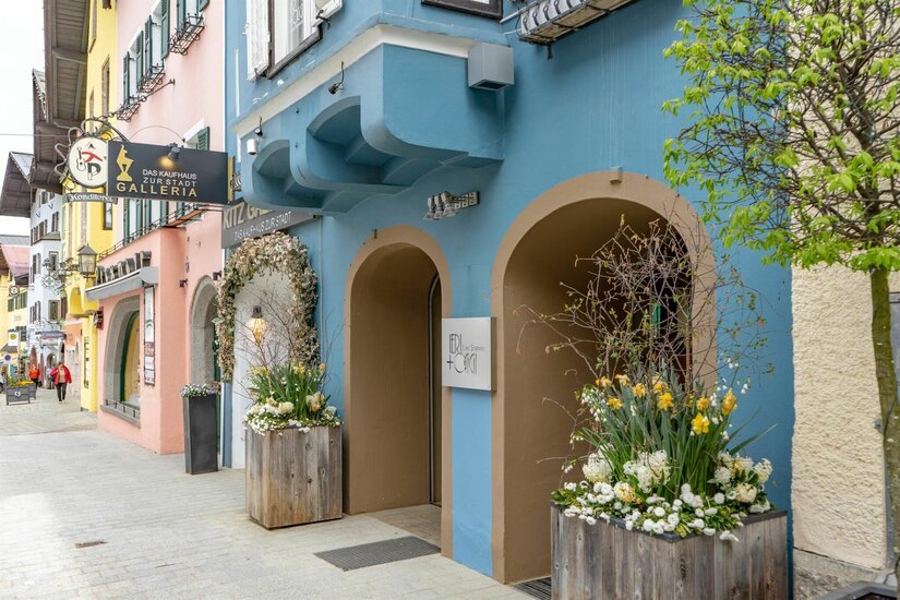 Eingangsbereich Ieri & Oggi Blaue Hausfassade mit Rundbogen-Eingängen und hölzernen Blumenkästen in einer gepflasterten Fußgängerzone.