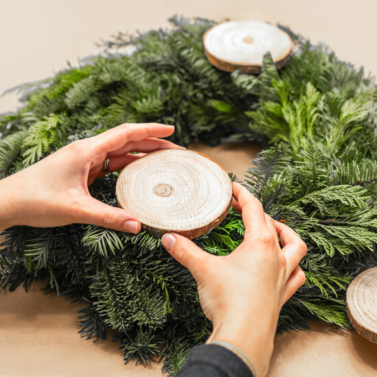 A green Advent wreath with two small wooden discs attached to it