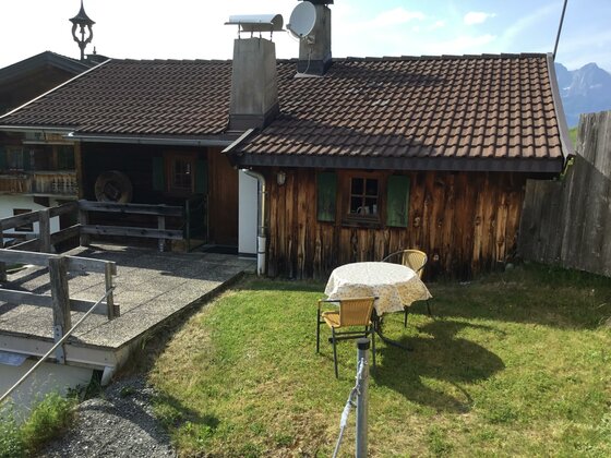 Terrasse am Bauernhof Sinnersberg Rustikale Holzhütte mit Terrasse, Rasenfläche und einer Sitzgruppe im Freien.
