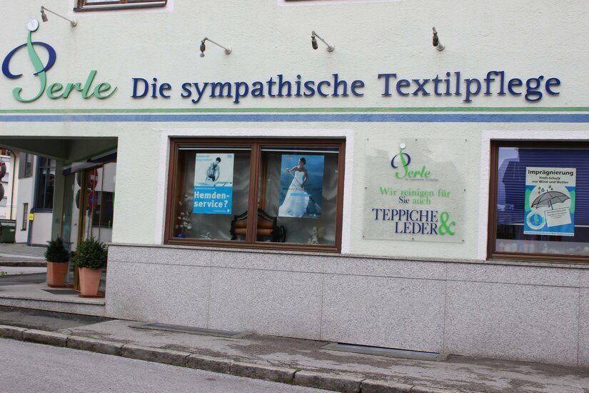 Perle Ein Geschäft mit der Beschriftung „Perle - Die sympathische Textilpflege“. Es bietet Dienstleistungen für Textilien und Leder an.