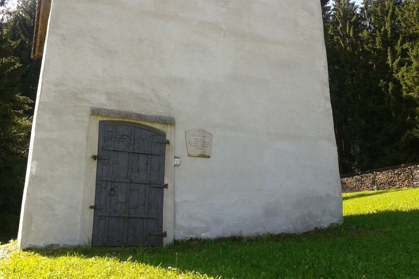 Pulverturm Ein schlichtes Gebäude mit einer dunklen Holztür steht auf grünem Gras. Im Hintergrund sind Bäume zu sehen.