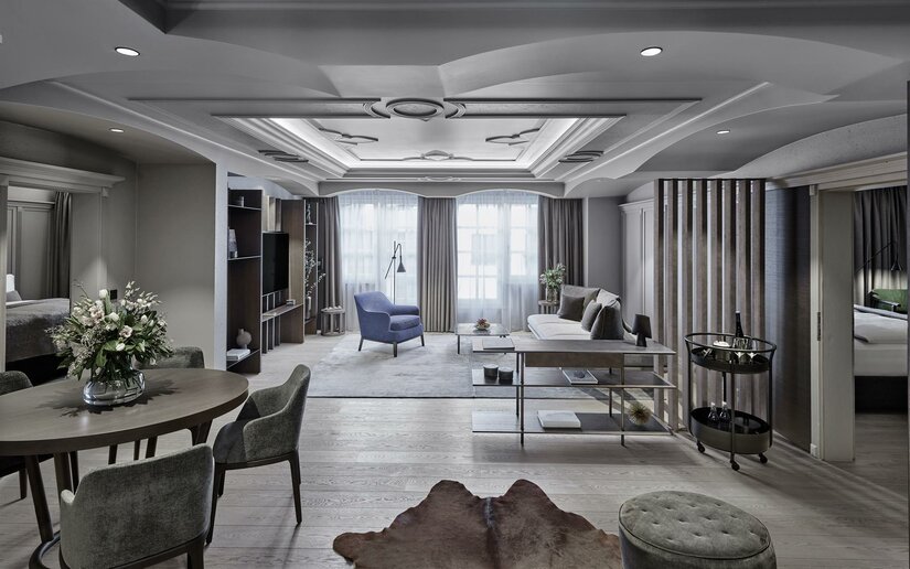 Deluxe Suite Residenz Weisses Rössl Modern eingerichteter Wohnbereich einer Hotelsuite mit Esstisch, Sofa und Sessel.