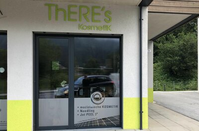 ThERE's Kosmetik Eingang Eingangsbereich von ThERE's Kosmetik mit Glasfront und grünem Schriftzug an der Fassade.