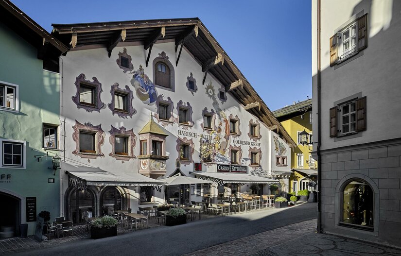 Fassade des Hotels Goldener Greif mit Wandmalereien und Außengastronomie in einer gepflasterten Gasse.