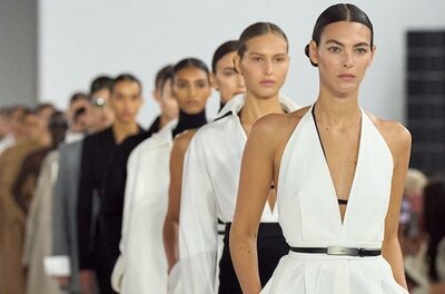 Mehrere Models laufen hintereinander in weißer und schwarzer Kleidung über einen Laufsteg.