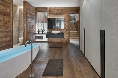 Ein modernes Badezimmer mit einer freistehenden Badewanne und Holzverkleidung. Der Raum hat große Fenster und warmen Holzboden.