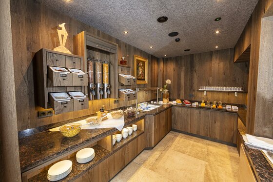 <p>Ein elegantes Frühstücksbuffet mit Holzwänden und gedämpfter Beleuchtung. Auf den Tischen befinden sich verschiedene Lebensmittel.</p>