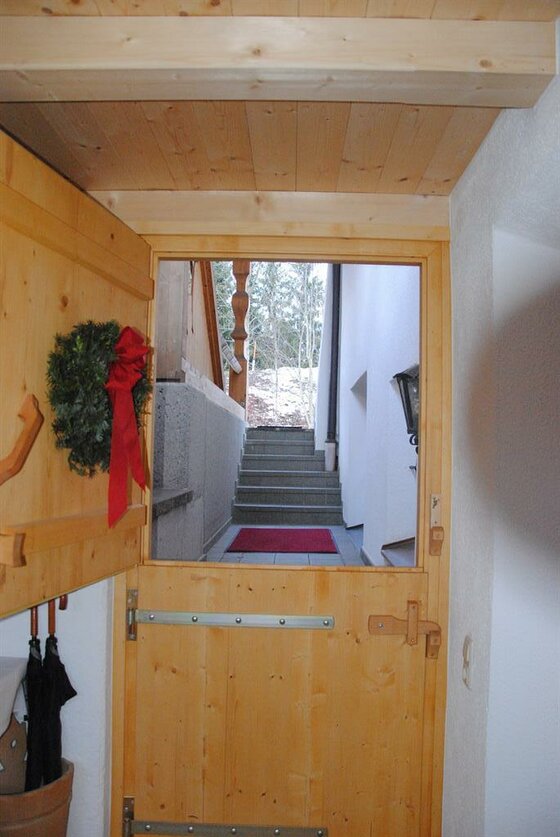 Blick durch eine geöffnete Stalltür aus Holz auf eine Außentreppe.