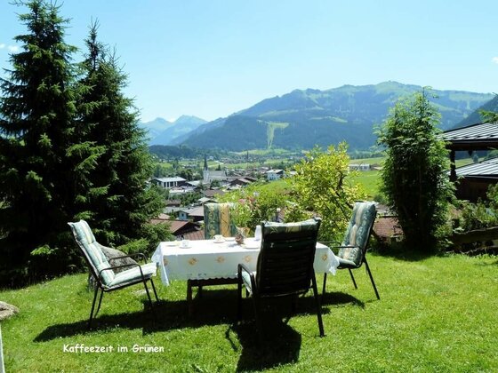 Gartentisch mit vier Stühlen auf einer Wiese vor Bergpanorama.