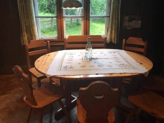 Essecke in der Villa Momo Runder Holztisch mit Stühlen vor einem Fenster in einer rustikalen Stube.