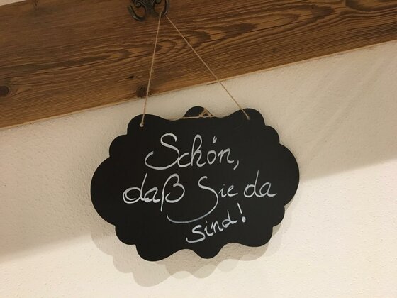 Schwarze Kreidetafel in Wolkenform mit dem handgeschriebenen Text: Schön, daß Sie da sind!
