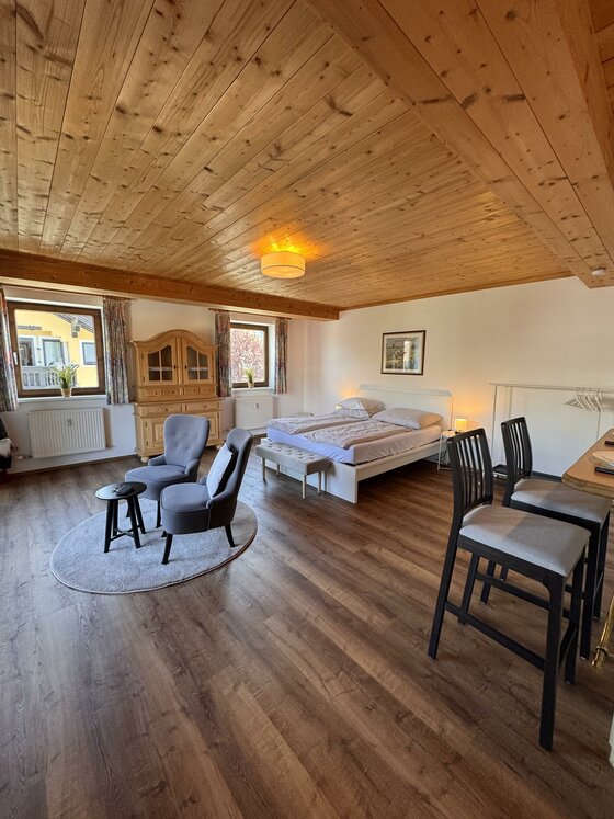 Modernes Zimmer mit Holzdecke, Doppelbett, Sitzecke und Laminatboden.