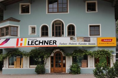Fassade des Geschäfts Hermann Lechner für Farben und Künstlerbedarf mit hellblauer Wand und Holztür.