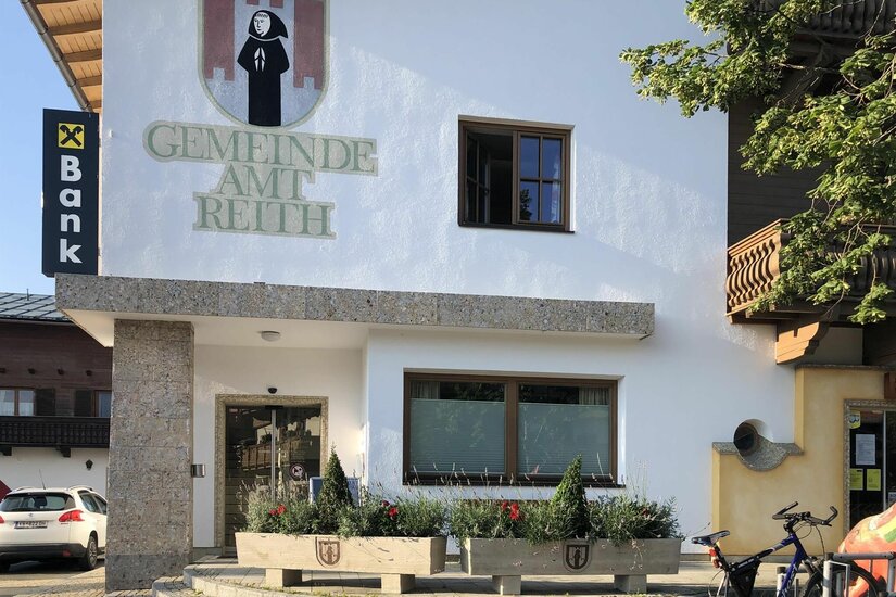 Gemeindeamt Reith Außenansicht des Gemeindeamts Reith mit Wappen und Schriftzug an der weißen Fassade.