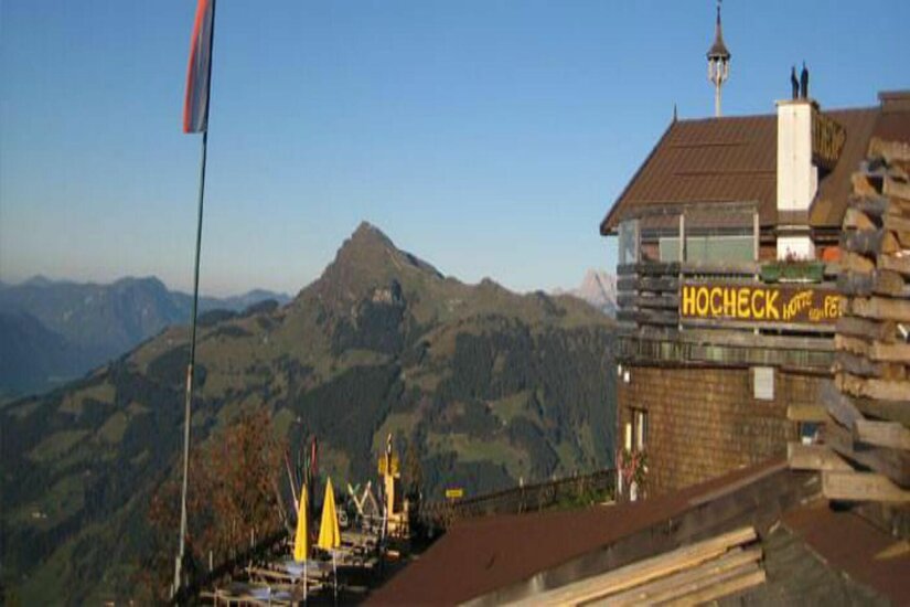 Hocheckhütte im Sommer Blick von der Hocheckhütte auf ein bewaldetes Bergpanorama mit markantem Gipfel unter blauem Himmel.