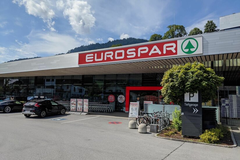 Außenansicht eines Eurospar-Supermarktes mit Parkplatz und Fahrrädern vor dem Eingang.