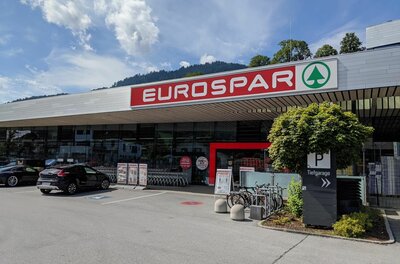 Außenansicht eines Eurospar-Supermarktes mit Parkplatz und Fahrrädern vor dem Eingang.