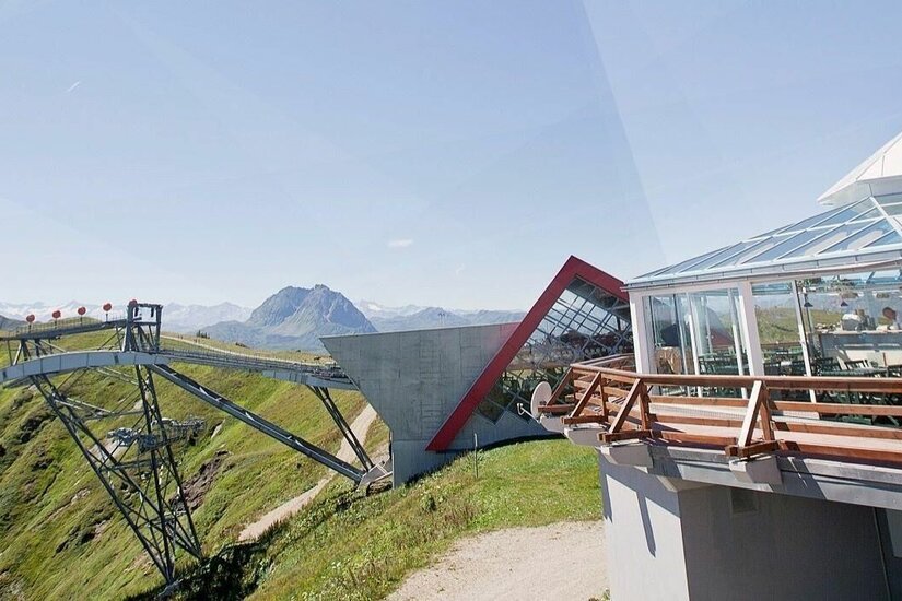 Bergrestaurant Pengelstein Moderne Bergstation mit Glaspavillon und Seilbahnstütze vor alpinem Panorama.