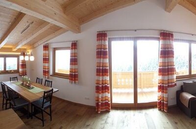 Wohnung 02 im Kleinlehenhof Moderner Wohn- und Essbereich mit Holzbalkendecke, Küchenzeile, Esstisch und Ecksofa.