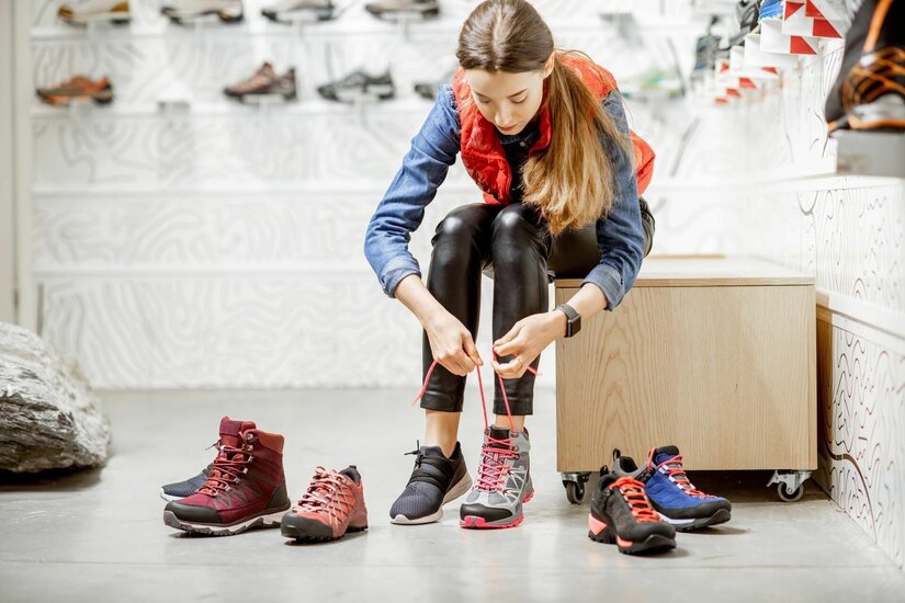 Schuhberatung bei Sport Pepi Eine Frau sitzt in einem Sportgeschäft und schnürt einen grauen Wanderschuh.