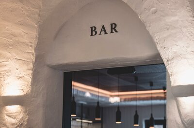Eingang zur Mocking Bar Eingangsbereich einer Bar mit Rundbogen und weißem Mauerwerk.