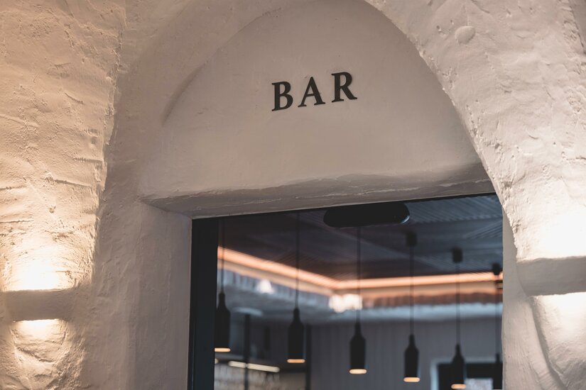 Eingangsbereich einer Bar mit Rundbogen und weißem Mauerwerk.