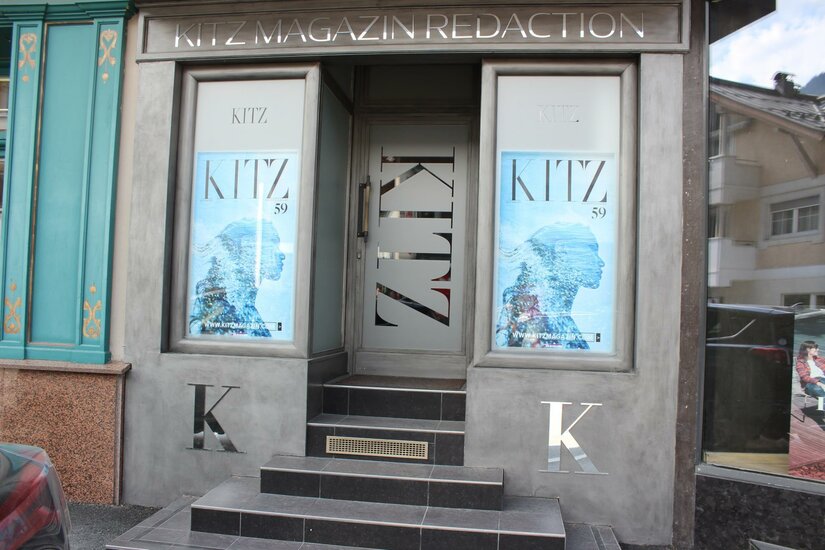 Ein modernes Geschäft mit Glaseingang und auffälligen Werbeflächen. Die Fassade ist in Grautönen gehalten und zeigt das Logo "KITZ".