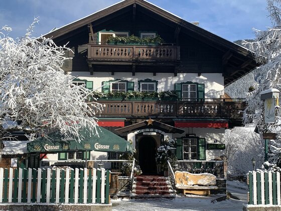 Hotel Villa Licht im Winter Alpines Hotelgebäude mit Holzbalkonen und schneebedeckten Bäumen im Vordergrund.