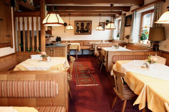 Frühstücksraum im Mühlbergerhof Rustikaler Frühstücksraum mit Holztischen, Eckbänken und roten Teppichläufern.