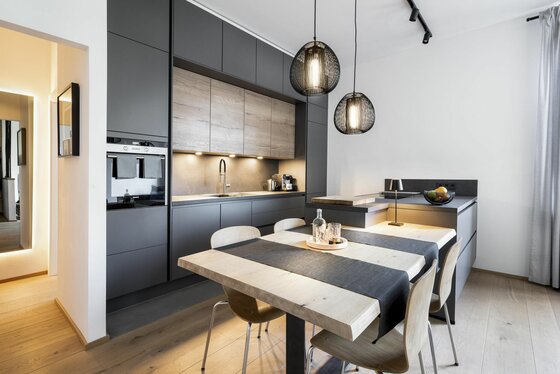 Küche im Apartment 1919 Moderne Küche in Anthrazit und Holzoptik mit Esstisch und zwei Pendelleuchten.