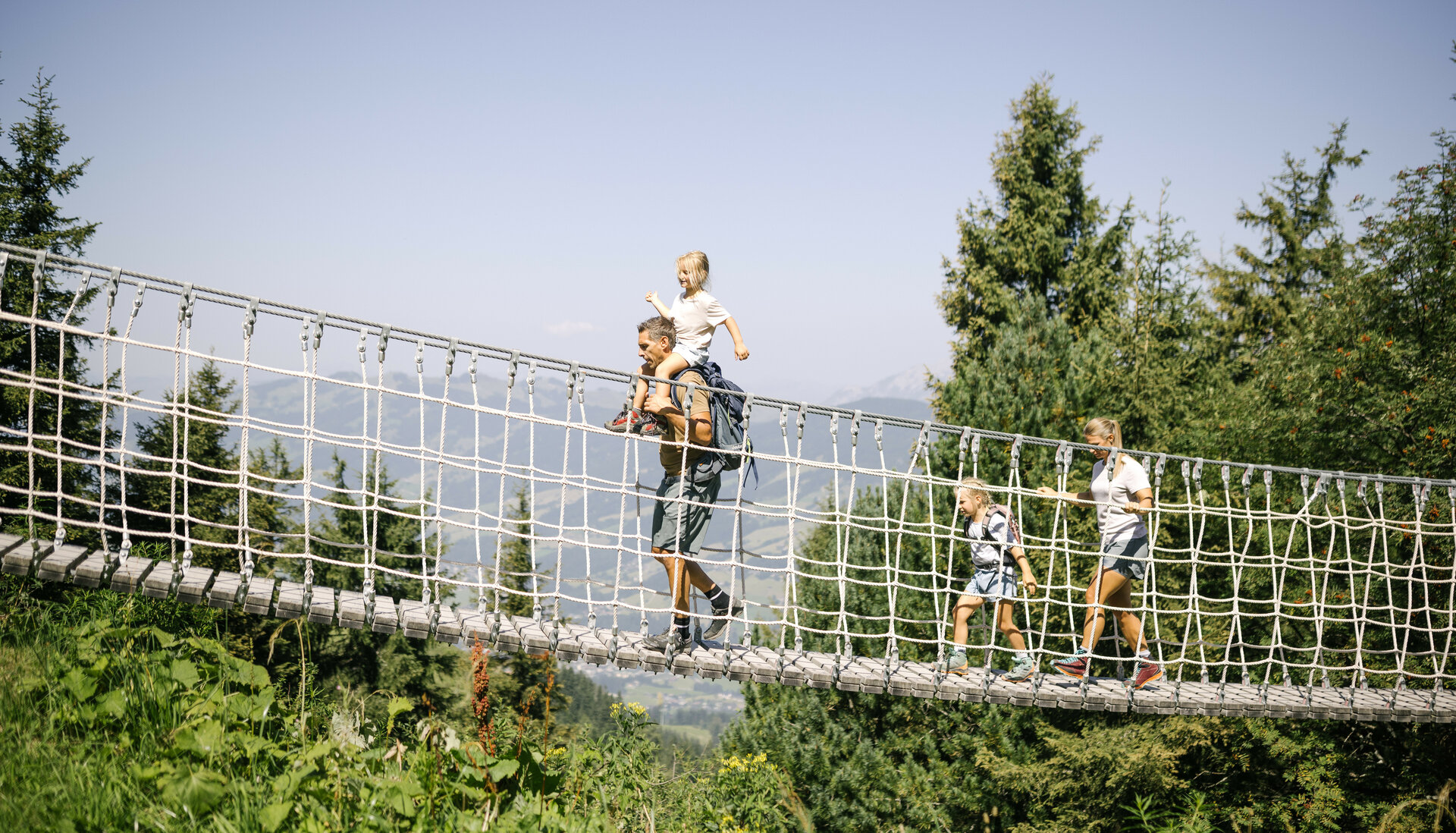 Familie geht über Seilbrücke