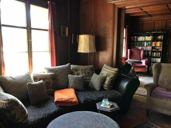 Villa Momo - Wohnzimmer Rustikales Wohnzimmer mit dunklem Sofa, gemusterten Kissen und Holzvertäfelung an den Wänden.