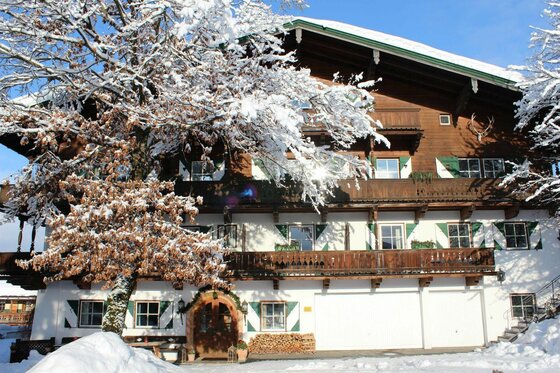 Römerhof im Winter Alpines Holzhaus mit Balkonen und schneebedeckten Bäumen im Winter.