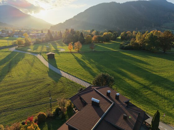 Ausblick <p>Eine malerische Landschaft mit einem großen, grünen Feld und einem klaren Himmel. Im Vordergrund ist das Appartement Golfweg und im Hintergrund sind sanfte Berge und Bäume zu sehen.</p>