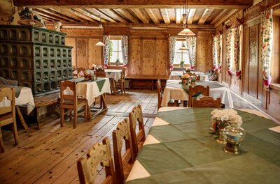 Gaststube Gasthof Alte Wacht Rustikale Gaststube mit Holztischen, Kachelofen und holzgetäfelten Wänden.